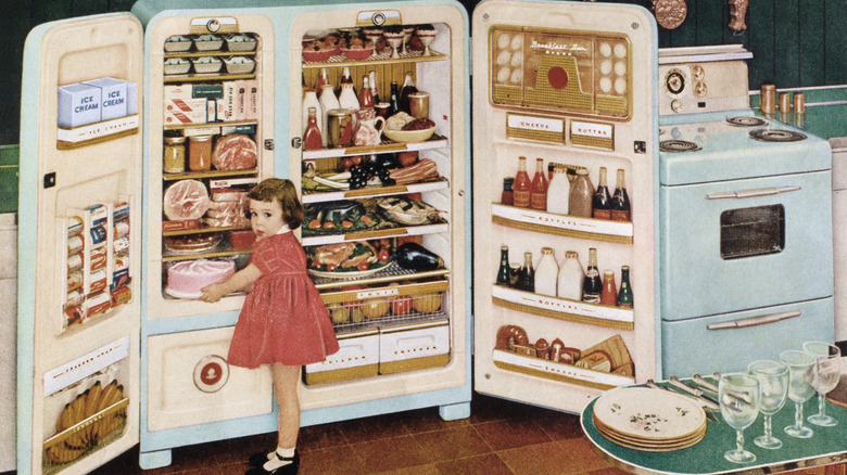 A 1950s print ad for the Kelvinator Fabulous Foodarama shows a little child pulling a cake from the open refrigerator