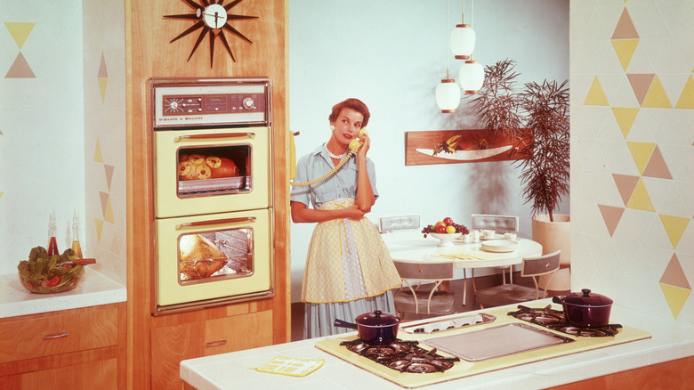 A 1950s-era housewife talks on the telephone in a retro kitchen