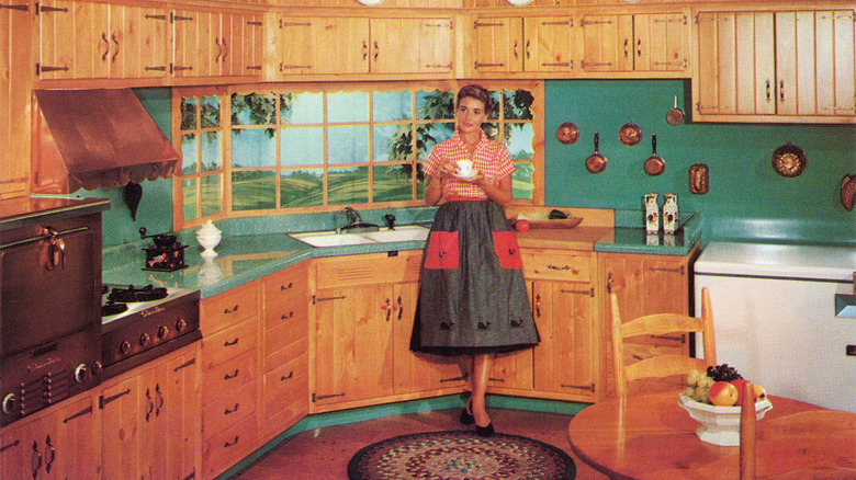 Vintage image of a woman standing in a kitchen filled with knotty pine cabinets