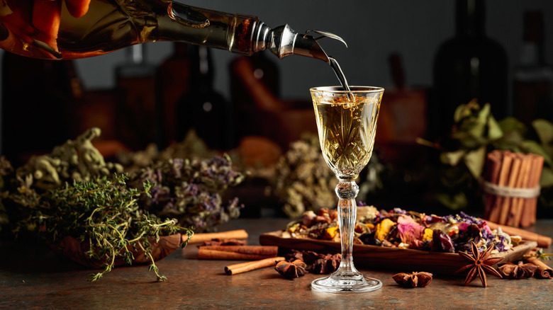 Herbal liqueur with herbs and spices on table