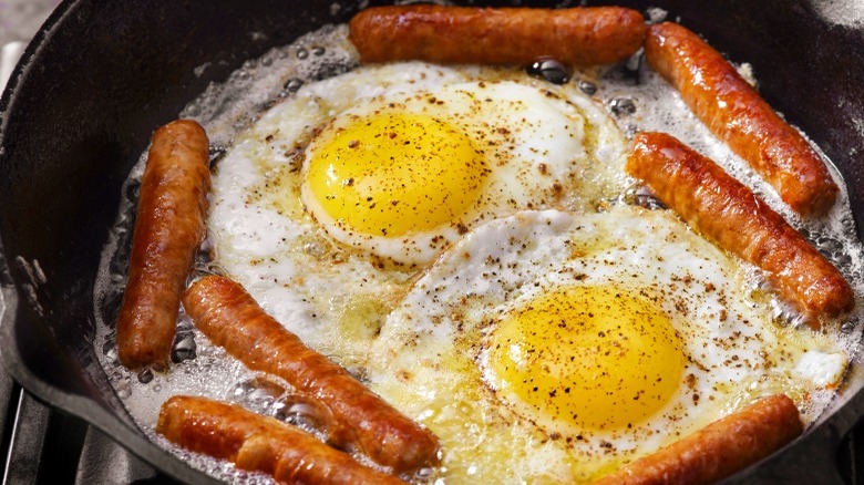 Sausage patties cooking with eggs
