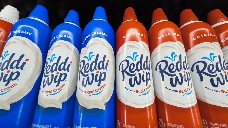 Eight cans of Reddi Wip whipped cream against a black background