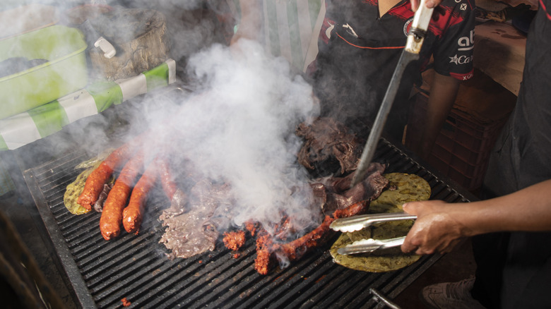 person cooking meats on grill