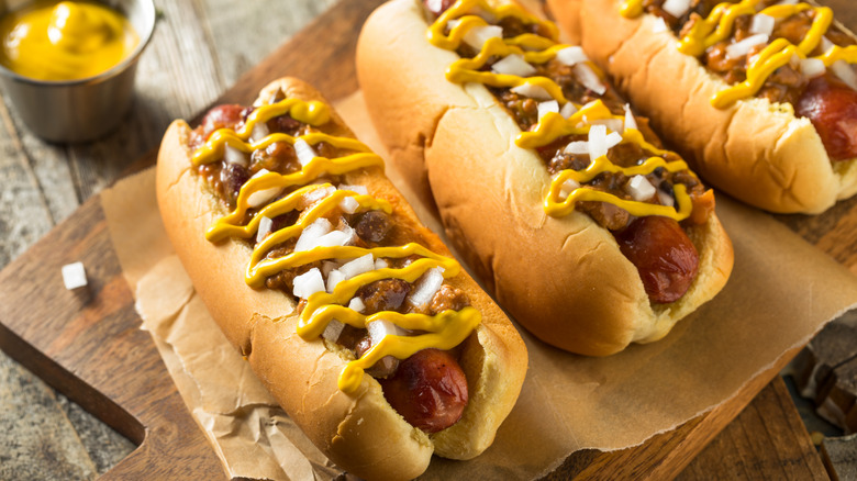 michigan hot dogs sit next to each other on a wooden cutting board
