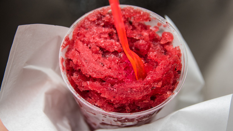 Cup of red water ice in a plastic cup with red plastic spoon