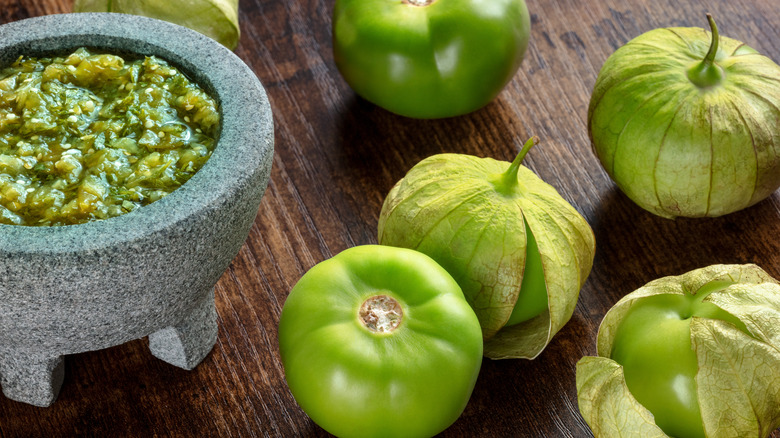 fresh tomatillos alongside salsa verde