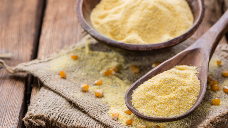 Cornmeal in a bowl and wooden spoon.