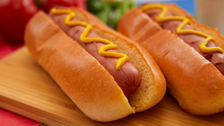 Two hot dogs, in buns, dressed with mustard