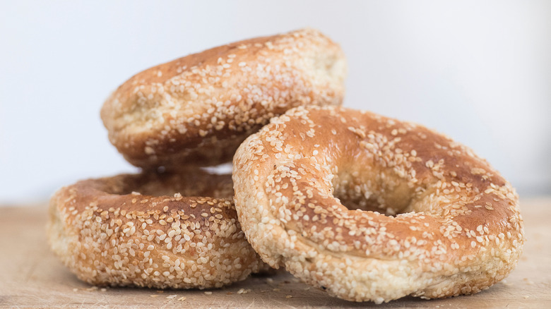 Close up of three Montreal sesame seed bagels on a cutting board.
