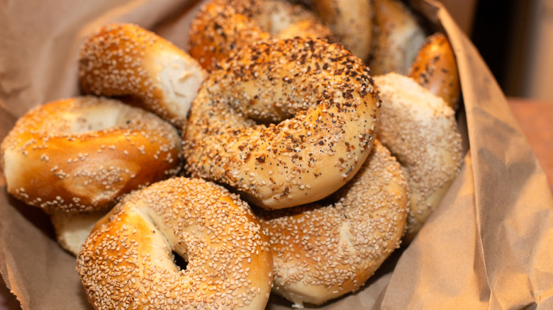sesame seed, everything, and poppy seed bagels in a brown paper bag