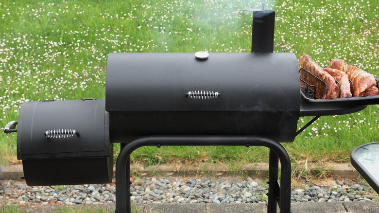 Offset smoker with tray of uncooked ribs