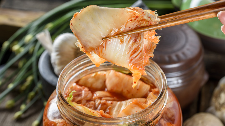 Person picking up piece of kimchi with chopsticks