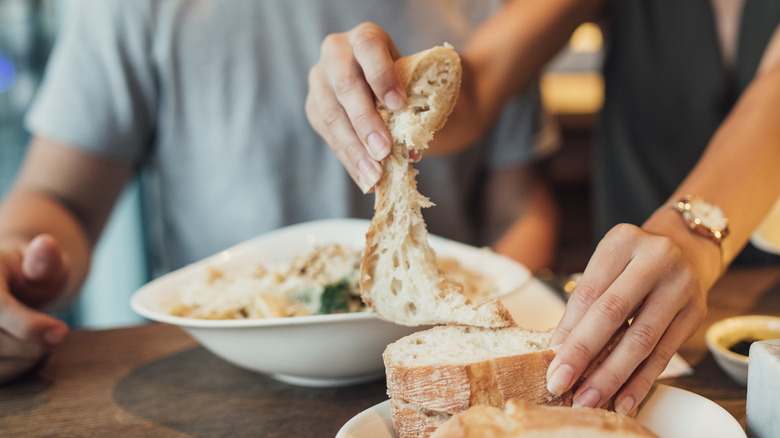 Woman taking bread piece from loaf