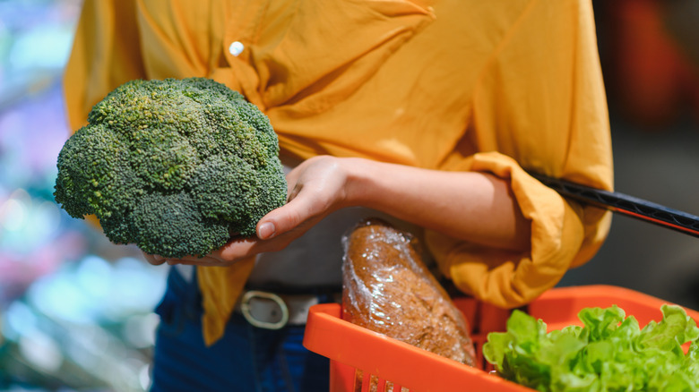 Shopper buying broccoli.