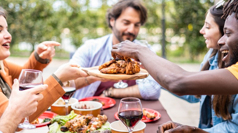 friends enjoying barbecue at a table outdoors