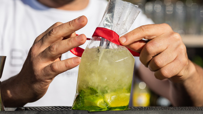 A bartender packages a cocktail