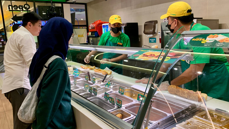 Subway employees assembling sandwiches for customers ordering