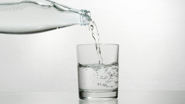 Mineral water poured into glass form glass bottle