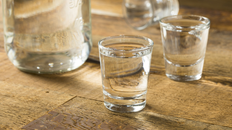 Clear liquor in shot glasses on wooden table