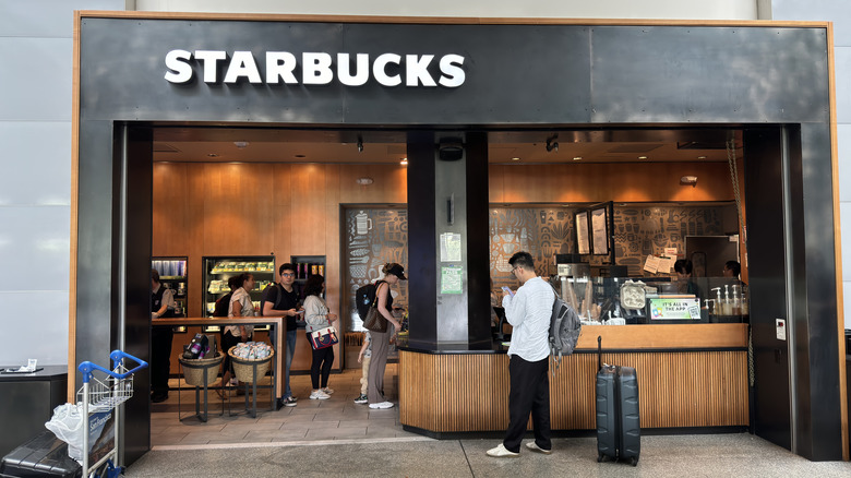 A narrow Starbucks storefront with people waiting in line