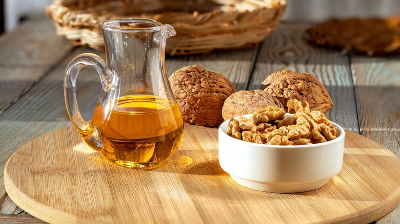 Jug of of oil next to walnuts