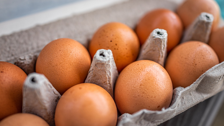 A closeup of a dozen brown eggs in cardboard container