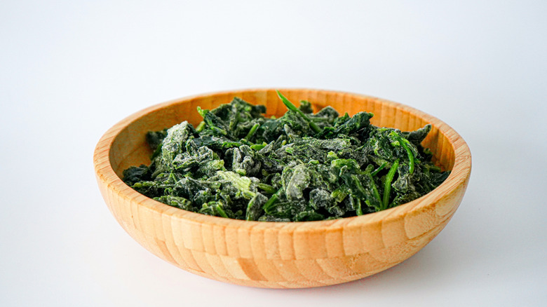 Wooden bowl of frozen spinach leaves