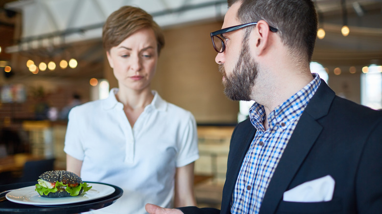 Someone speaks to a frowning server.
