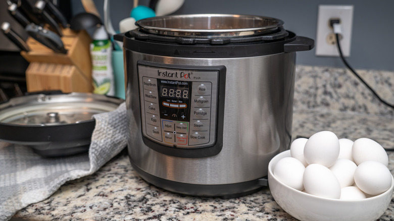 An Instant Pot on a counter next to eggs.