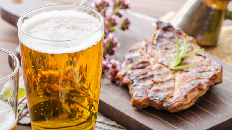 Glass of beer next to grilled pork chop