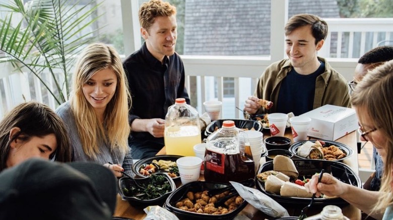 People gathered around a table eating catered Chick-fil-A