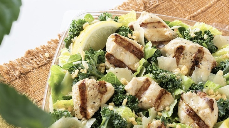 Grilled Chick-fil-A nuggets on a bed of greens with a lemon wedge