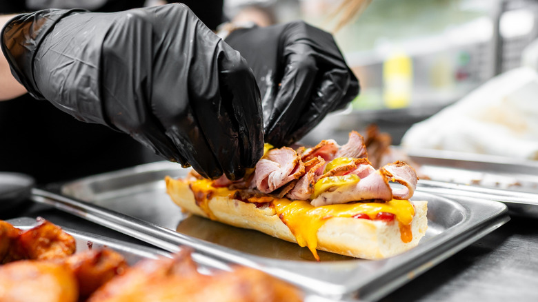 Cook preparing hoagie sandwich.
