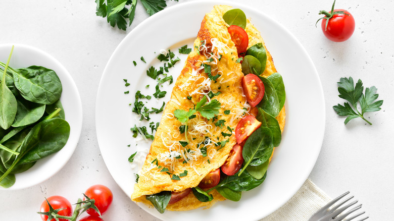 Omelet with spinach and tomatoes on a white plate