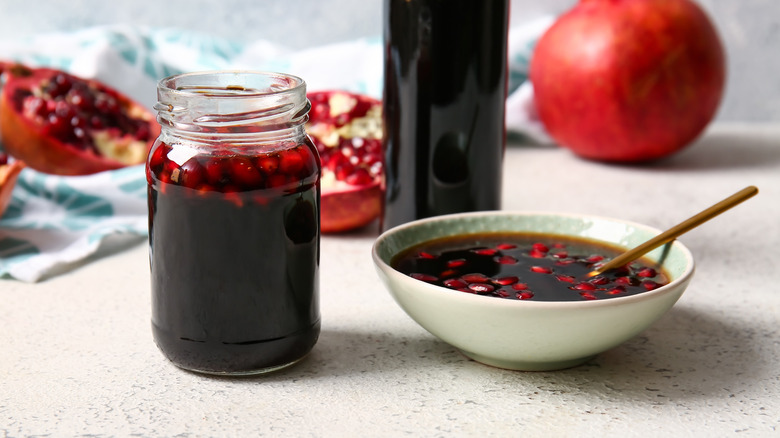 A jar and a bowl of pomegranate molasses are on a table.