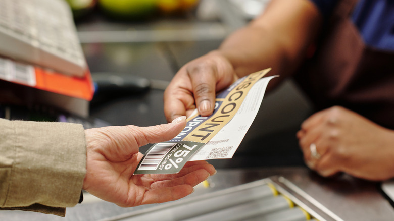 A cashier hands a customer a receipt with a coupon