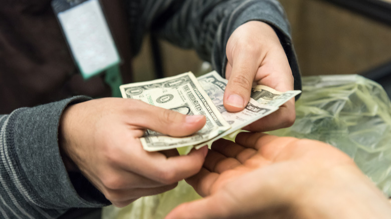 Closeup of a cashier handing cash back to a person's outstretched hand