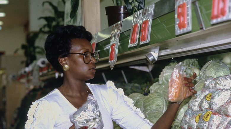 A woman examines produce in a 1980s supermarket