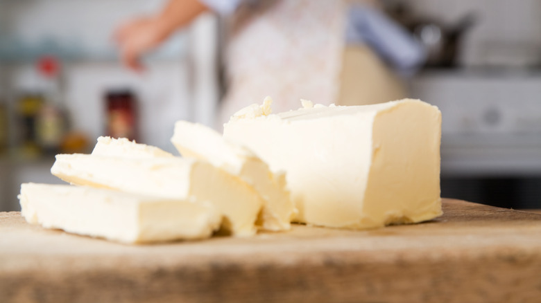 Rustic, homemade butter sits on a top of a wooden cutting board