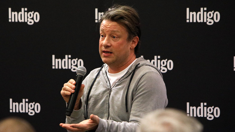 Jamie Oliver giving a talk with one of his cook books