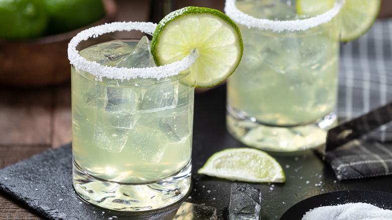 Two margaritas on the rocks with lime wheel garnish