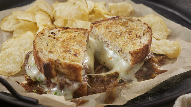 French onion Gruyère grilled cheese on parchment paper with potato chips