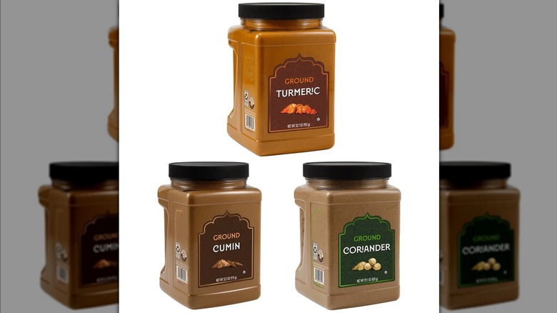 Three cannisters of spices sit against a white background.