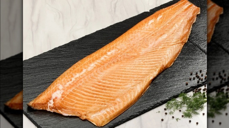 A slab of smoked salmon on a black slate