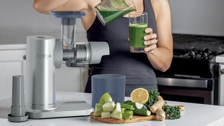Someone makes a glass of green juice with the Ninja Juicer