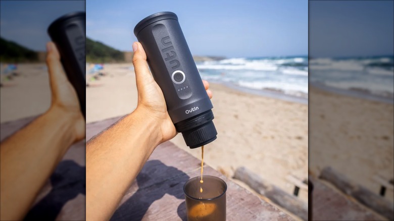 Hand pours coffee out of a OutIn Nano Portable Espresso Machine Travel Kit