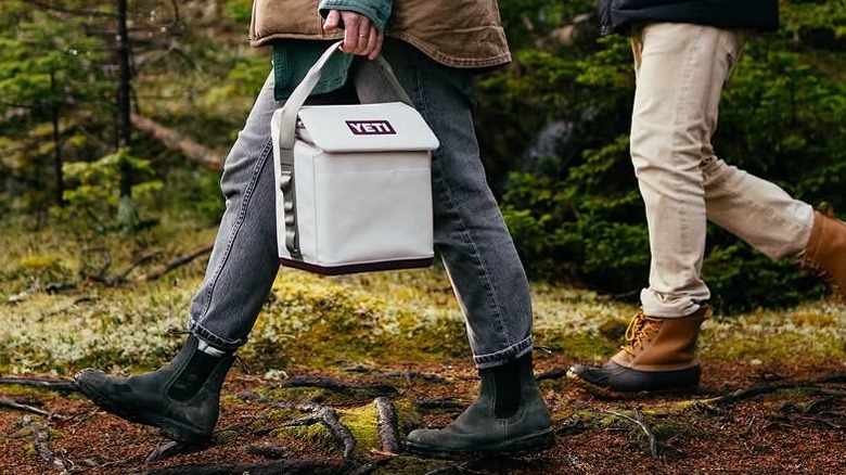 A hiker or camper carries a Yeti lunch tote.