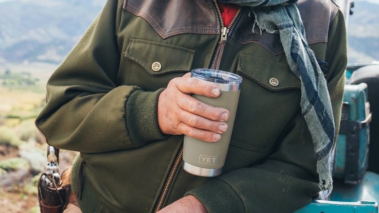 A outdoors person holds a YETI tumbler.