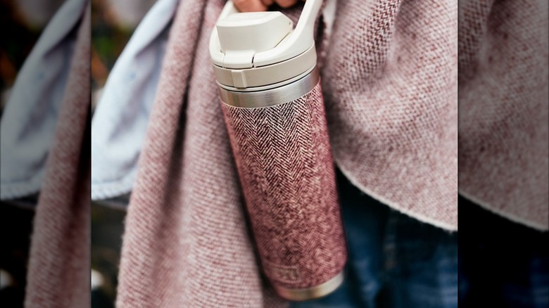 A hiker carries a YETI water bottle.