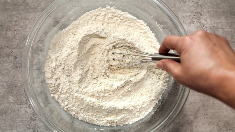 hands whisking pancake mix in bowl